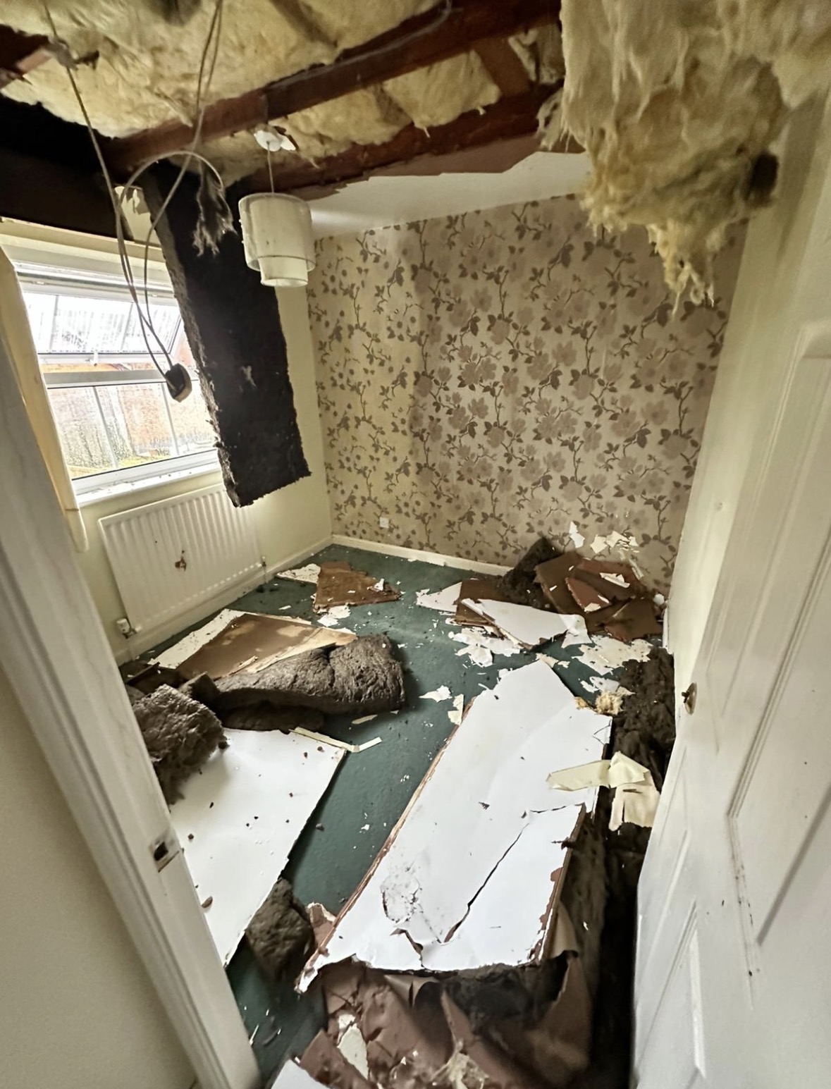 Smaller bedroom with damaged plasterboard removed and insulation exposed