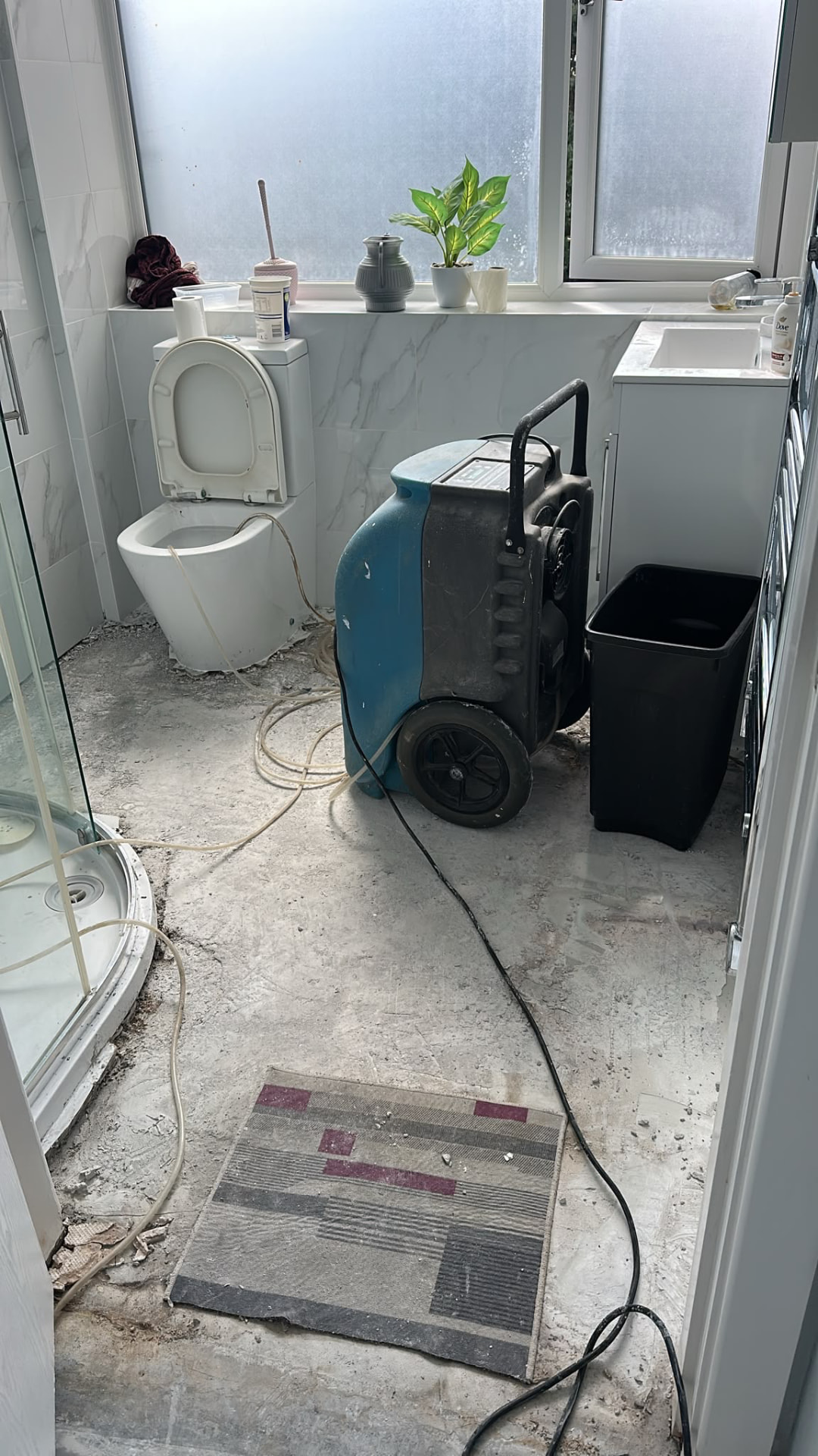 Dehumidifier operating in a stripped bathroom with exposed floor